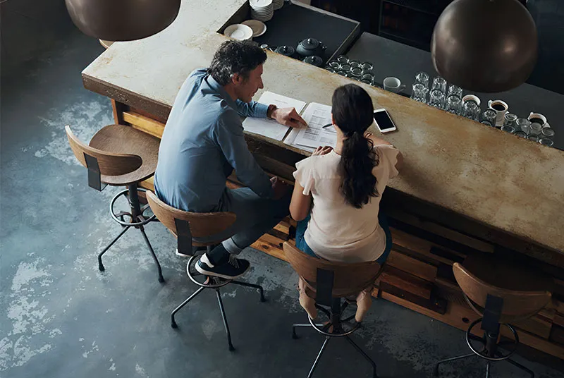Two people working at a café front bar