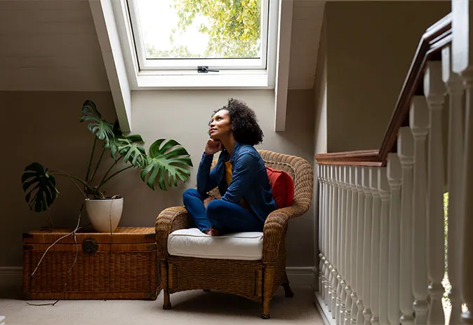 Woman sitting indoors looking out a roof window